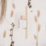 Ivy & Sage Honey & Almond reed diffuser styled in a neutral botanical flat lay with warm natural textures.