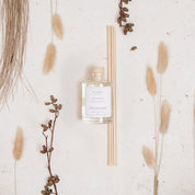 Ivy & Sage Santal 13 reed diffuser styled in a neutral botanical flat lay with natural textures.
