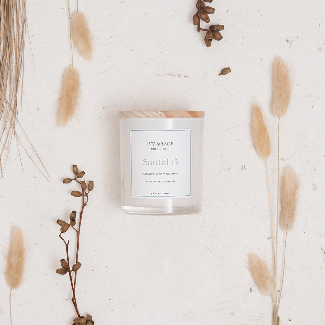 Ivy & Sage Santal 13 glass candle flat lay styled with soft neutral botanicals and natural textures.