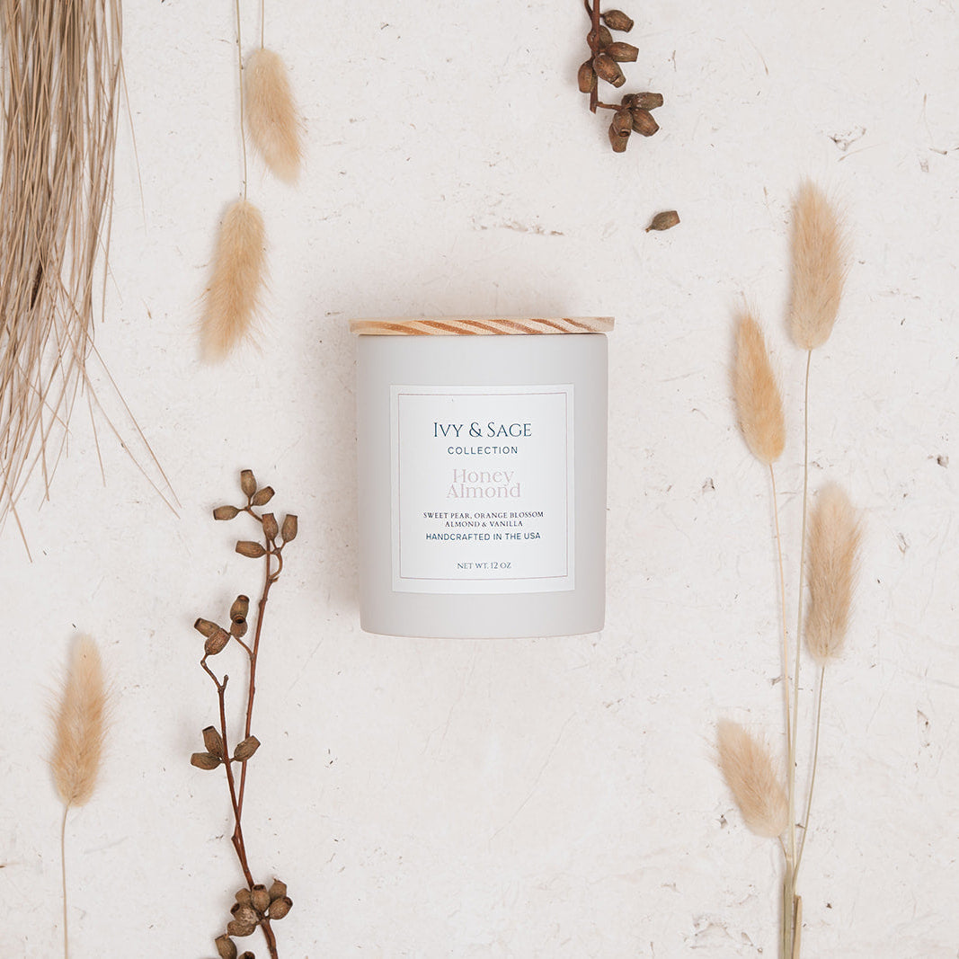 Ivy & Sage Honey & Almond ceramic candle styled in a neutral botanical flat lay