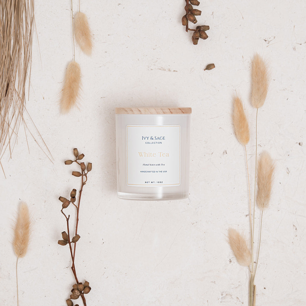 Ivy & Sage White Tea glass candle flat lay styled with soft neutral botanicals and natural details.
