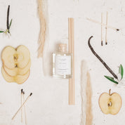 Ivy & Sage Smoked Vanilla reed diffuser styled in a neutral flat lay with apple, vanilla and natural botanical details.