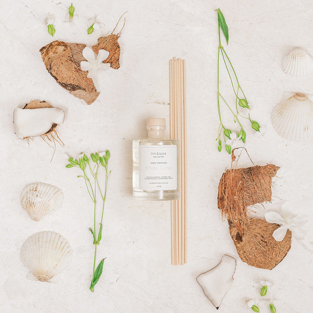 Ivy & Sage White Lotus reed diffuser styled in a botanical flat lay with white flowers, coconut and natural textures.