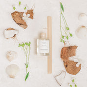 Ivy & Sage White Lotus reed diffuser styled in a botanical flat lay with white flowers, coconut and natural textures.