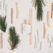 Ivy & Sage Palo Santo reed diffuser styled in a neutral botanical flat lay with palo santo wood and greenery.