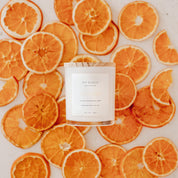 Ivy & Sage Satsuma glass candle flat lay styled with fresh orange slices.